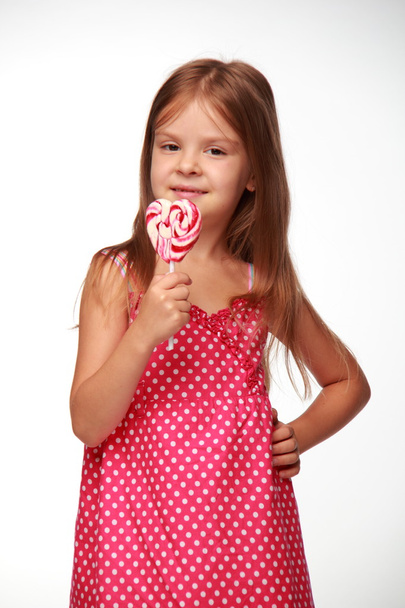 Little girl in pink dress with lollipop - Zdjęcie, obraz