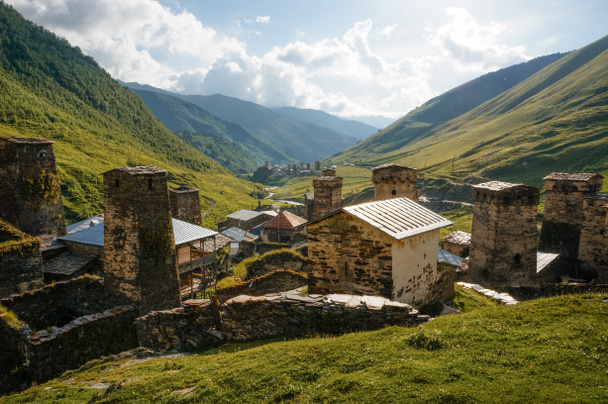 Nézd a füves terület a régi, elöregedett, vidéki épületek és hegyek a háttérben, Ushguli, svaneti, Grúzia  - Fotó, kép