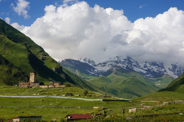Nézd a zöld füves rét házak, épületek és hegyek a háttérben, Ushguli, svaneti, Grúzia - Fotó, kép