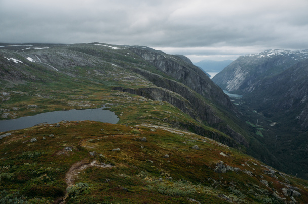 kilátás a hegy lejtőjén a fű és a kis tó, a hegyek a háttérben, Norvégia, Hardangervidda Nemzeti Park - Fotó, kép