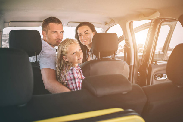 Happy family on a road trip in their car. Dad, mom and daughter are traveling by the sea or the ocean or the river. Summer ride by automobile - 写真・画像