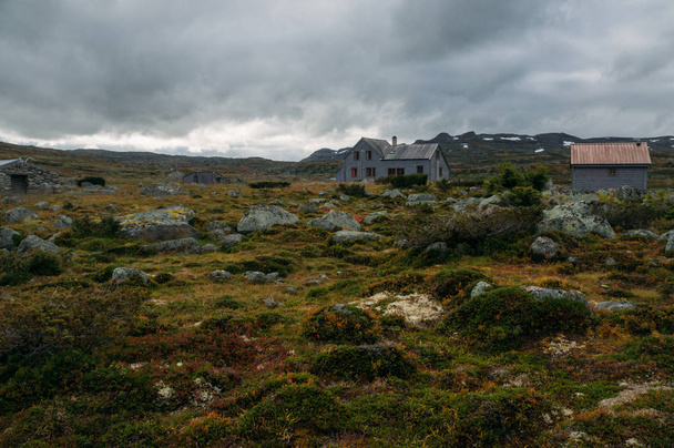 a fű és a kövek házak szerint viharos ég, Norvégia, Hardangervidda Nemzeti Park területén - Fotó, kép