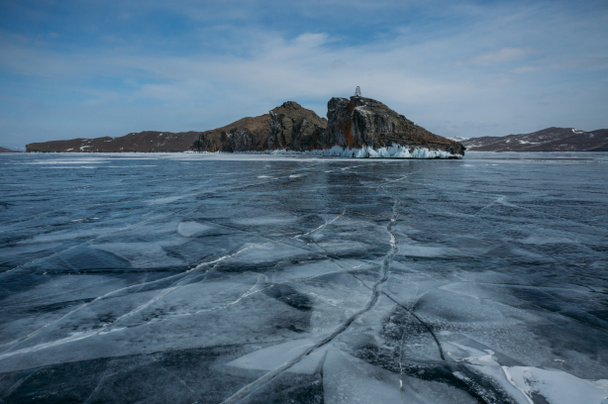 View of ice covered water surface of lake and rock formations on background, Russia, Lake Baikal - Фото, зображення