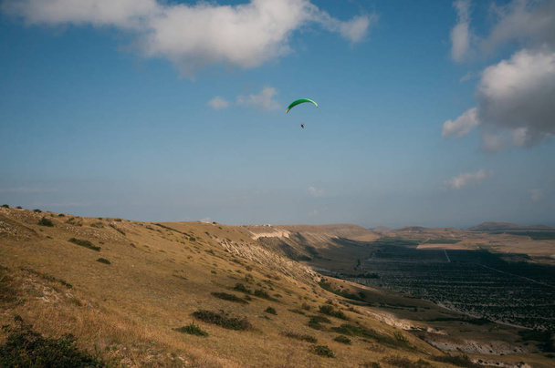 Parachutist gliding in blue sky over scenic landscape of Crimea, Ukraine, May 2013 - Photo, Image