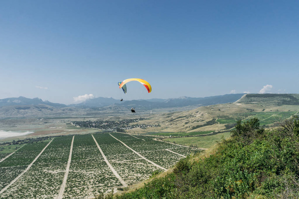 Parachutists gliding in blue sky over scenic landscape of Crimea, Ukraine, May 2013 - Photo, Image