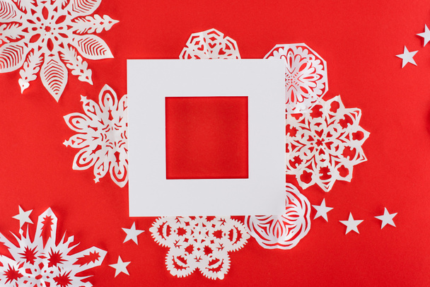 cadre de Noël blanc avec étoiles et flocons de neige en papier autour, isolé sur rouge
   - Photo, image