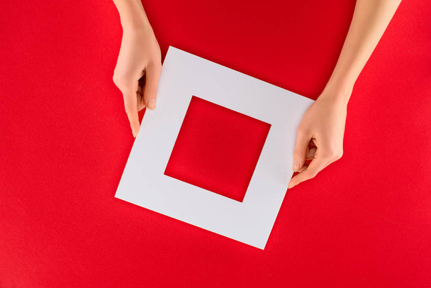 vue recadrée des mains féminines avec cadre blanc, isolées sur rouge
 - Photo, image