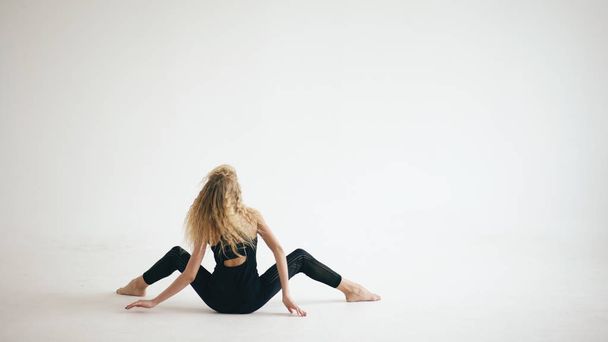 Modern beautiful teenage girl dancer dancing contemporary on white background indoors - 写真・画像