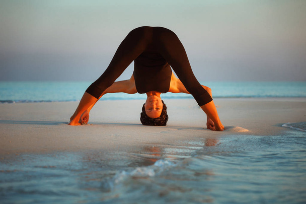 Séance de yoga d'été sur une belle plage dorée de virage avant à larges pattes - Prasarita Padottanasana I
 - Photo, image