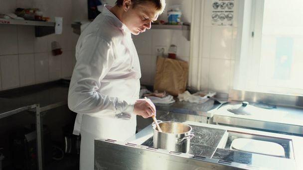 Professionele chef-kok man bereiden jus saus met kruiden op oven bij restaurant keuken - Foto, afbeelding