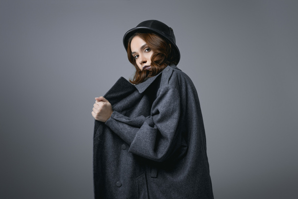 módní model představuje v podzimní kabát a vojenskou helmu, izolované Grey - Fotografie, Obrázek