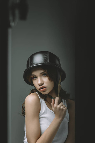 привлекательная молодая модель, позирующая в военном шлеме для модной съемки
 - Фото, изображение