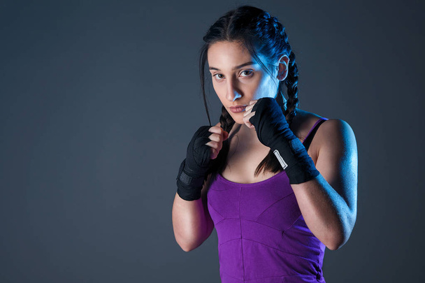 Female boxer makes a fight with a shadow, dark background with space for text. Strong and confident, she will be a champion. - Foto, Bild