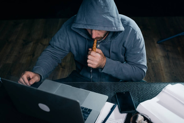 mysterious man hacker, hides his face under the hood and smokes a hookah - Φωτογραφία, εικόνα