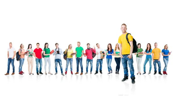 Large group of teenage students with books and backpacks standing together over white background. School, education, college, university concept. Blond guy with hands in pockets at the forefront  - Photo, Image
