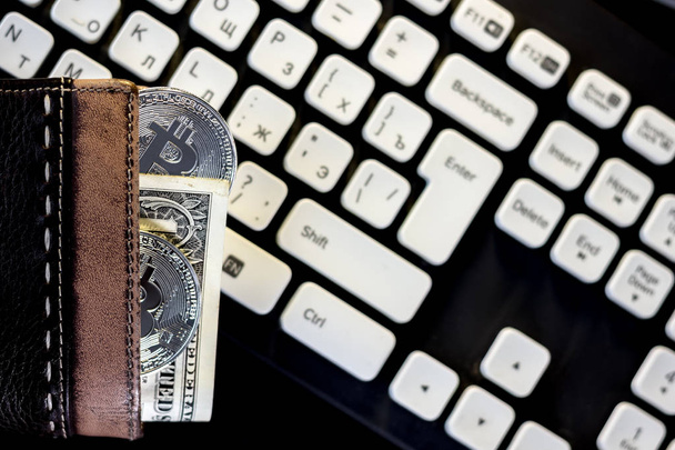 Πορτοφόλι με μετρητά και bitcoin κέρμα πάνω από το πληκτρολόγιο του υπολογιστή - Φωτογραφία, εικόνα