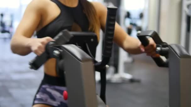 Woman trains arms and shoulders on simulator in gym - Filmagem, Vídeo