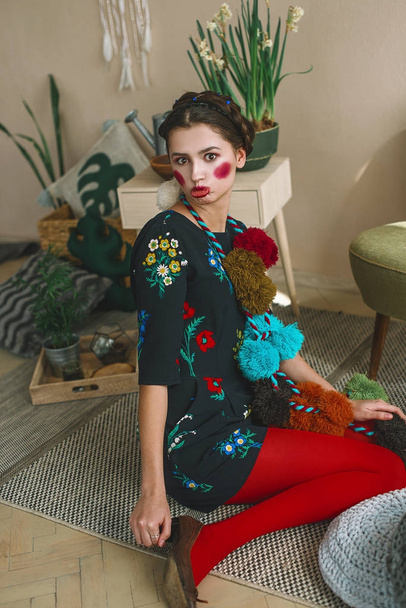 Fashionable beautiful brunette girl in a jumpsuit with floral embroidery with color makeup: red cheeks and lips. Granny chic style. Retouched portrait - Photo, image