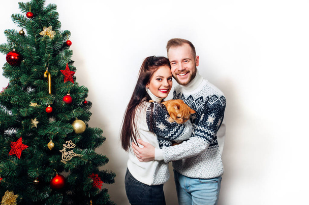 happy family couple in sweaters with cat near christmas tree on white background - Foto, Imagen