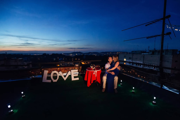 Verliefde paar op het dak van het huis met uitzicht op de avond c - Foto, afbeelding
