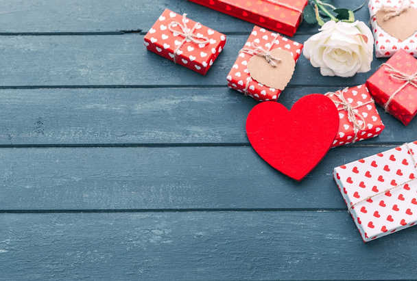 Gift boxes and red heart over wooden background. - Фото, изображение