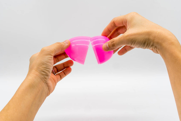 Τα χέρια, σπάζοντας ένα τεχνητό ροζ αυγό που απομονώνονται σε λευκό  - Φωτογραφία, εικόνα