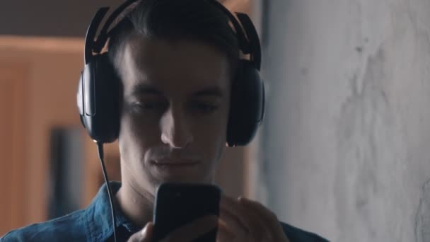 Młody człowiek z słuchawki do słuchania muzyki ze smartfona - Materiał filmowy, wideo