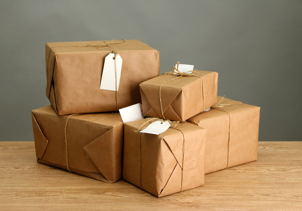 parcels boxes with kraft paper, on wooden table on grey background - Φωτογραφία, εικόνα