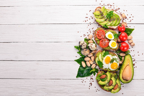 A set of avocado sandwiches, cherry tomatoes and quail eggs and chia seeds. On a wooden background. Top view. Free space for your text. - Foto, Imagen