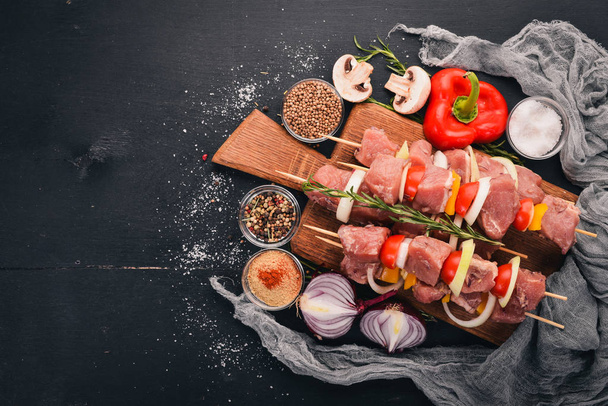 Raw kebab from meat on a wooden background with vegetables. Top view. Free space for text. - Foto, Imagen