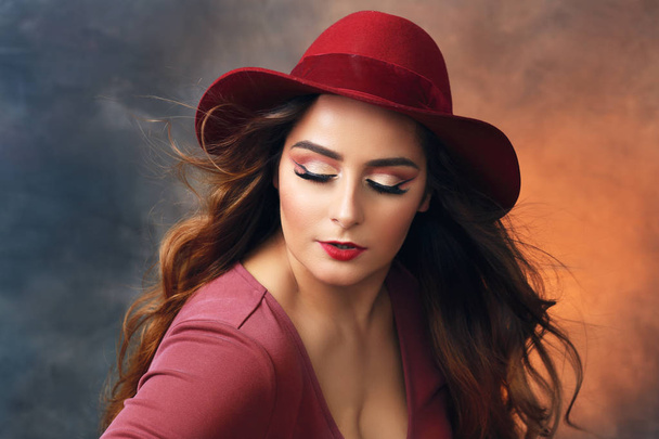 beautiful plus size woman in red dress and red hat posing at studio - Foto, immagini