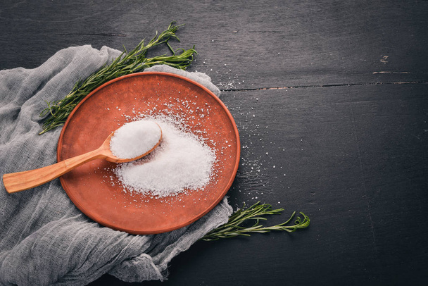 Salt in a wooden spoon on a plate. On a wooden background. Top view. Free space for text. - Photo, image