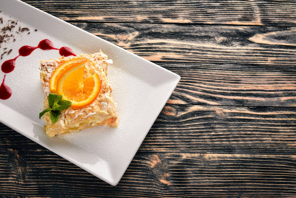 Layered cake with orange flavor. On a wooden background. Free space for your text. Top view. - Фото, изображение