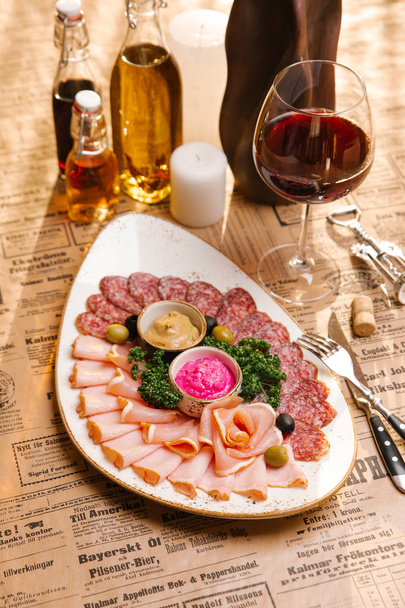 Vlees schotel geserveerd met mosterd en bieten mierikswortel, versierd met peterselie en olijven - Foto, afbeelding