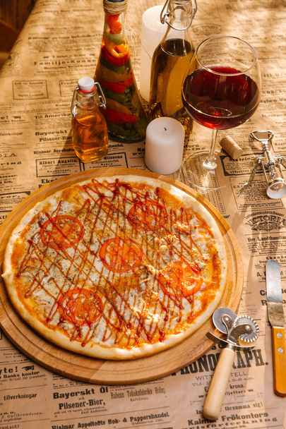 Kip pizza met tomaten, mozzarella en ketchup bovenop geserveerd op houten plank - Foto, afbeelding