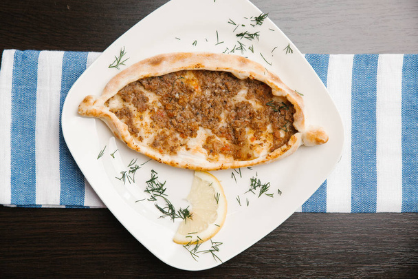 Adjarian khachapuri con queso, huevos y carne servida con trozo de limón en plato blanco
 - Foto, imagen