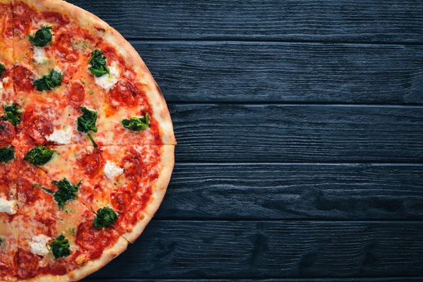 Neapolitan Pizza. Spinach, gorgonzola cheese, sausage salami. On a wooden background. Top view. - Фото, изображение
