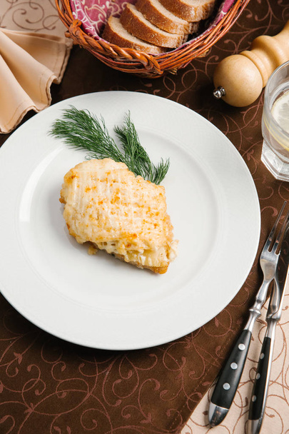 изысканный куриный шницель подается с укропом на белой тарелке со столовыми приборами, стаканом для воды, мясом для перца и ломтиками хлеба
 - Фото, изображение