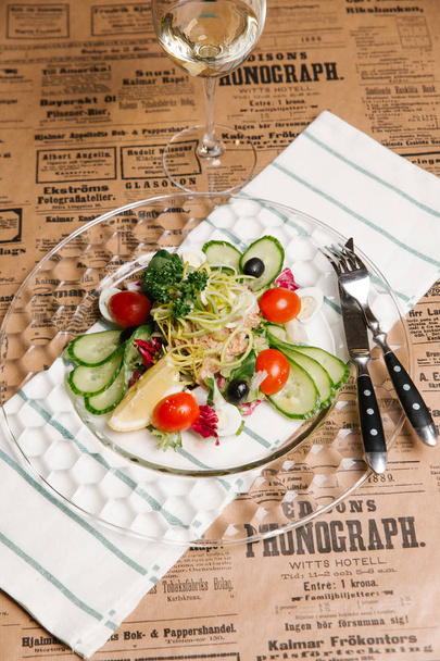 Salada de legumes com pepinos, alho-poró, azeitonas, atum e ovos de codorna servidos em prato de cristal
 - Foto, Imagem