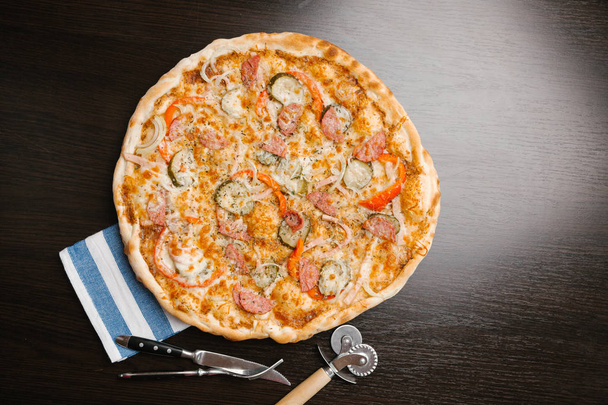 Vista superior da pizza com picles, salsichas, cebolas, pimentas, presunto e queijo
 - Foto, Imagem