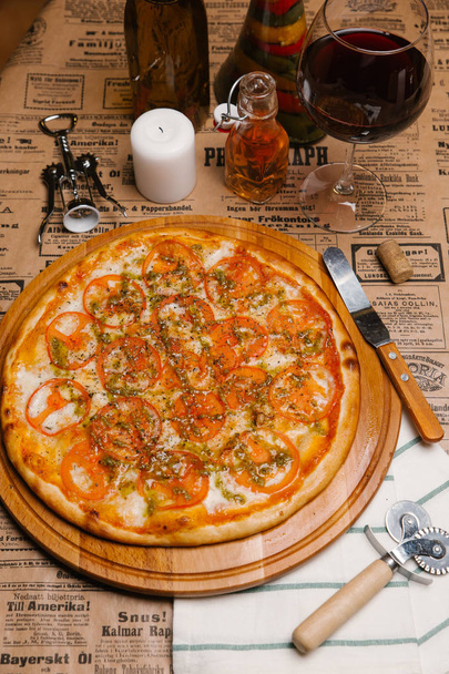 Pizza au fromage aux tomates et sauce servie sur plateau en bois
 - Photo, image