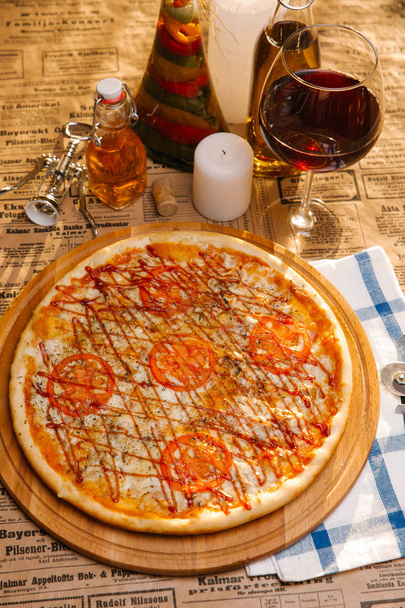 Pizza au poulet avec mozzarella, tomates et ketchup sur le dessus servi sur une planche de bois
 - Photo, image