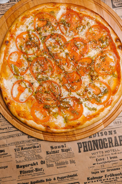 Pizza au fromage aux tomates et sauce servie sur plateau en bois
 - Photo, image
