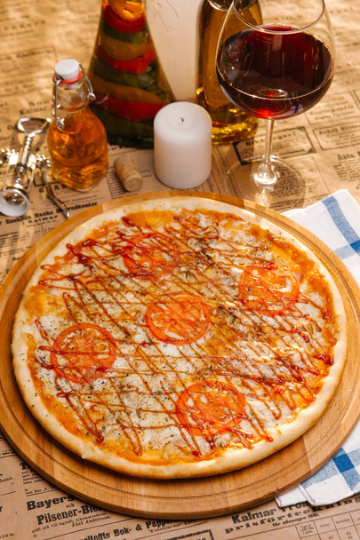 Куриная пицца с моцареллой, помидорами и кетчупом сверху подается на деревянной доске
 - Фото, изображение