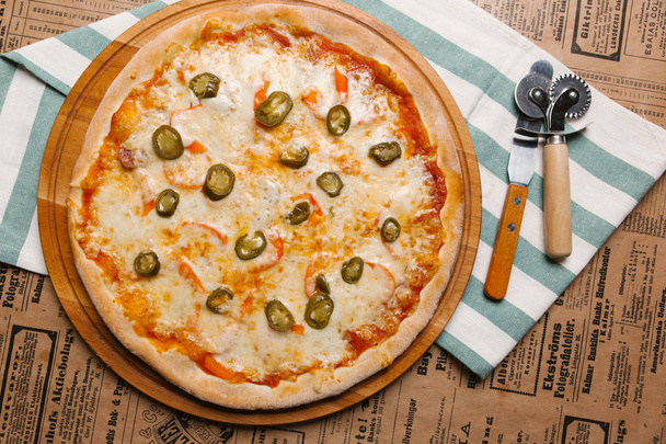Pizza de queso con jalapeño servida en bandeja de madera y servilleta rayada
 - Foto, Imagen
