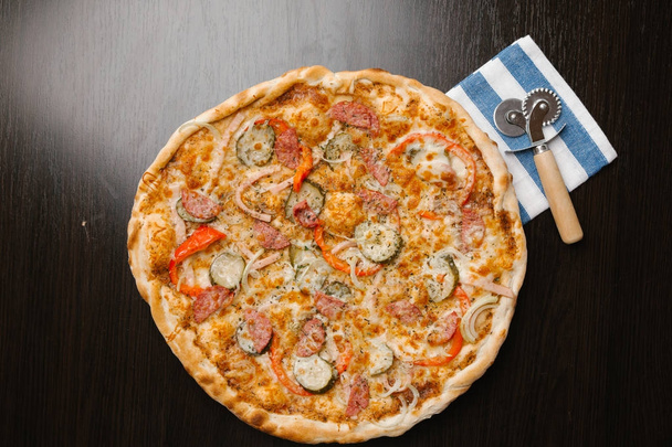 Πίτσα με αγγουράκι τουρσί, λουκάνικα, κρεμμύδια, πιπεριές, το ζαμπόν και τυρί - Φωτογραφία, εικόνα