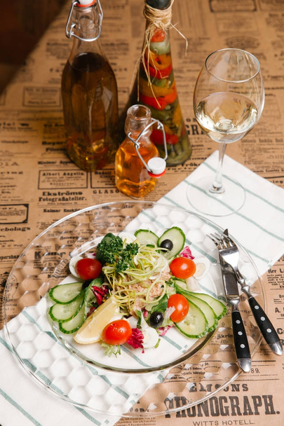 Salada de legumes com pepinos, alho-poró, azeitonas, atum e ovos de codorna servidos em prato de cristal
 - Foto, Imagem