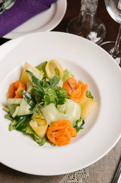Salaatti kesäkurpitsa viipaleita, lohta, arugula ja juustoa tarjoillaan valkoinen levy
 - Valokuva, kuva