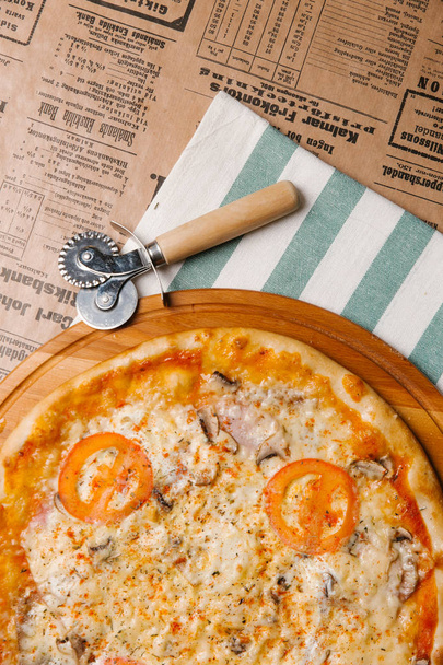 Cheese pizza with tomatoes, ham and mushrooms served on wooden tray - Photo, Image
