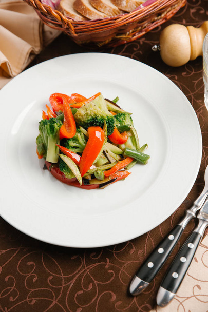 Овочевий салат з брокколі, болгарським перцем та зеленою квасолею на білій тарілці
 - Фото, зображення